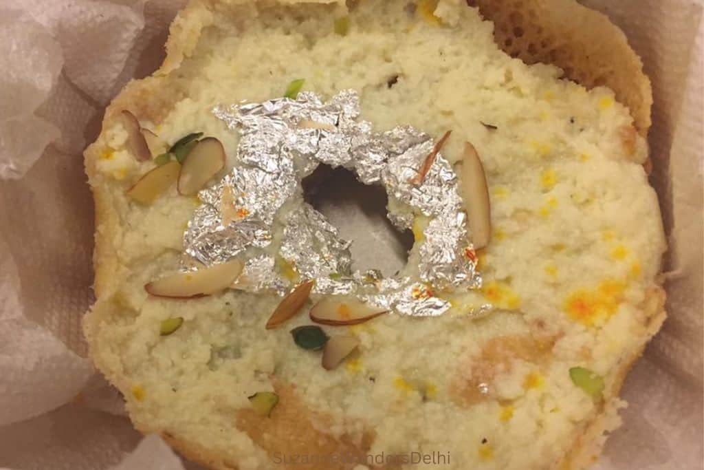 close up of ghevar from above with silver foil and almonds, saffron and pistachios