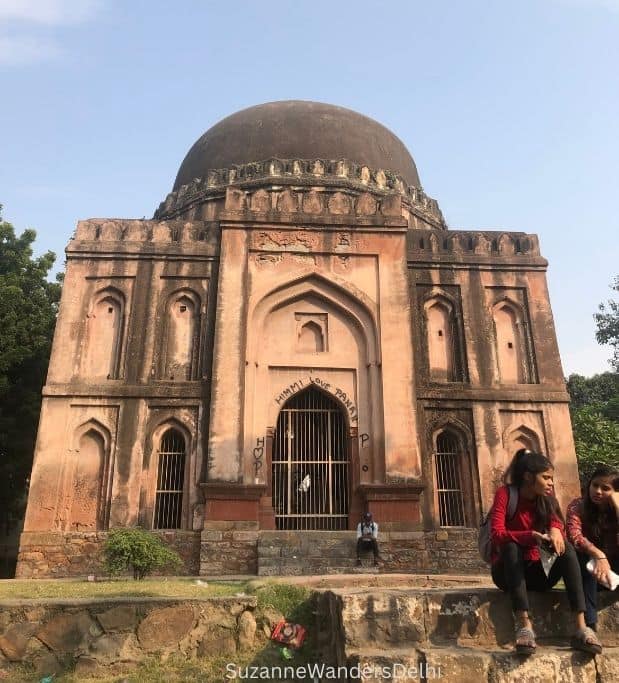 two girls sitting in front of Khale Khan's tomb, with blue sky in background